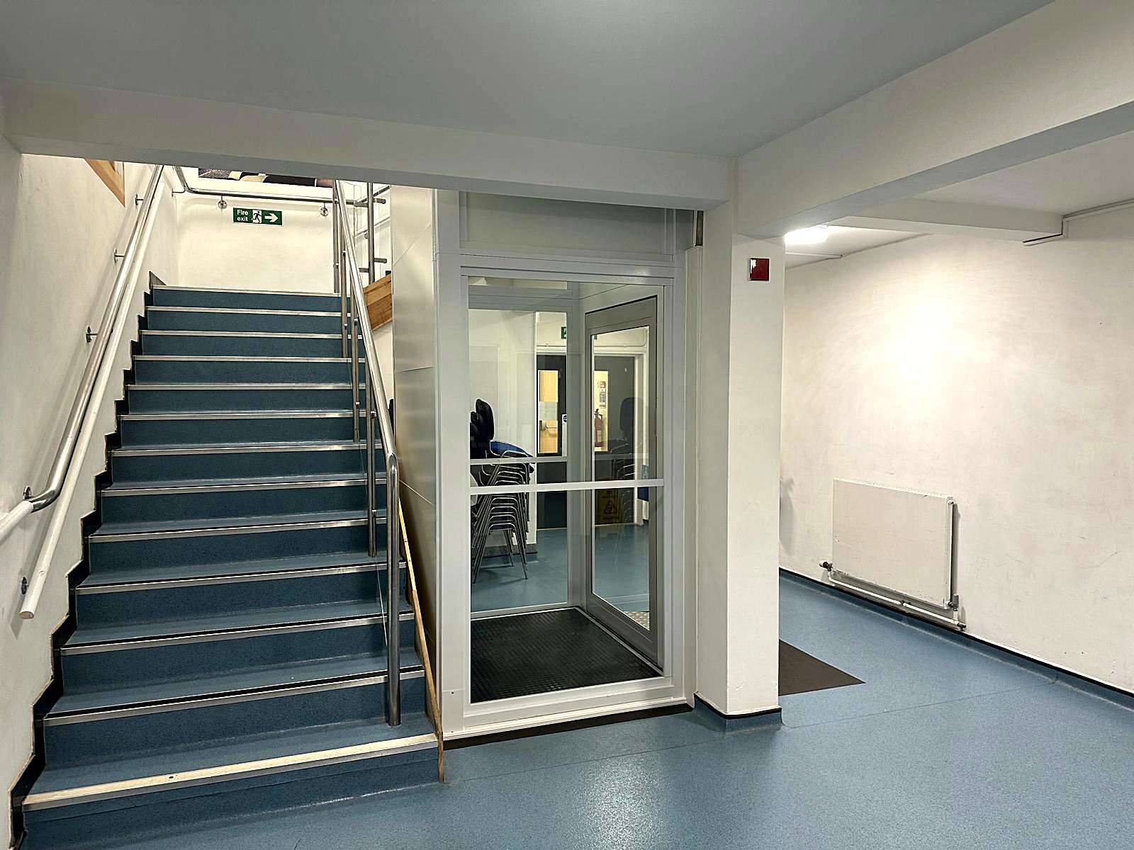 Hydraulic platform lift beside a staircase in a recreation centre