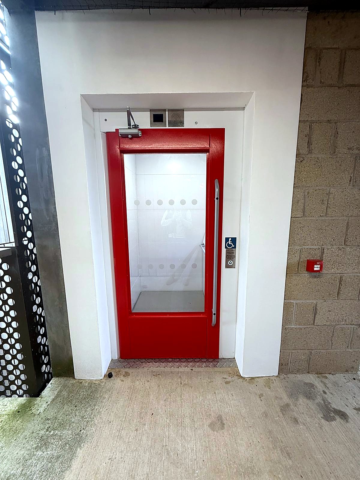 Screw-driven platform lift with red door