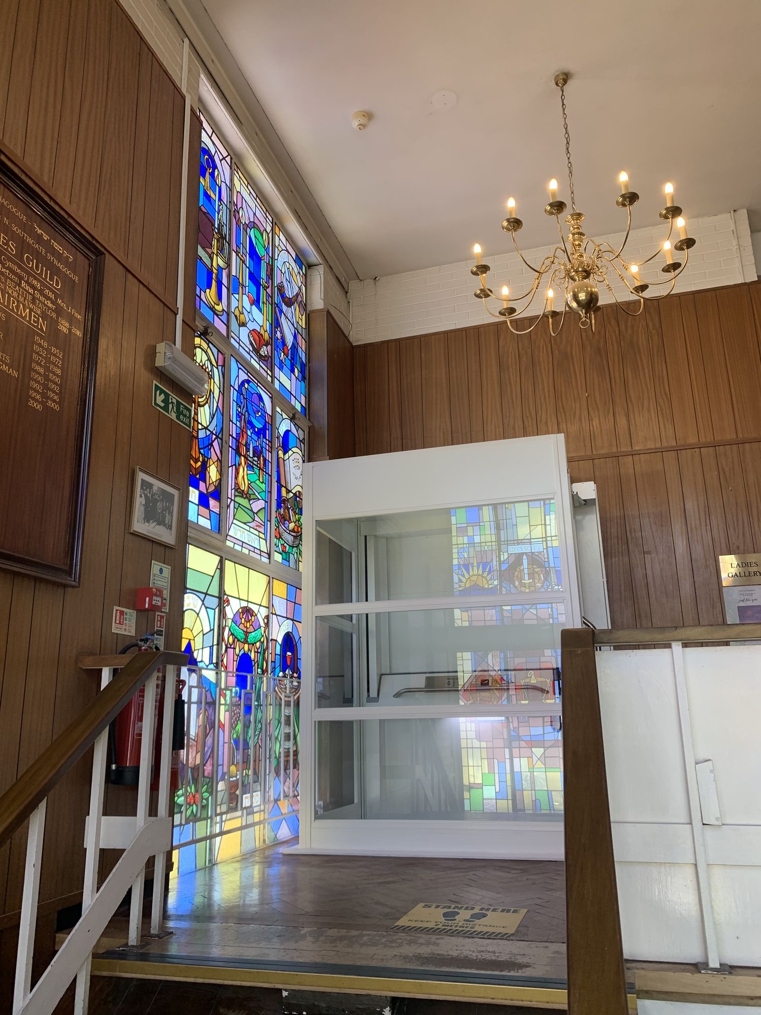 Traction platform lift in a hall with a chandelier and stained glass